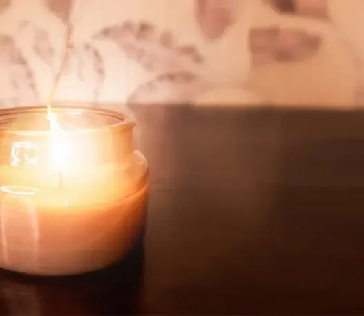 A lit candle glows on a table