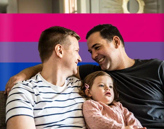 Two people on couch smiling with child