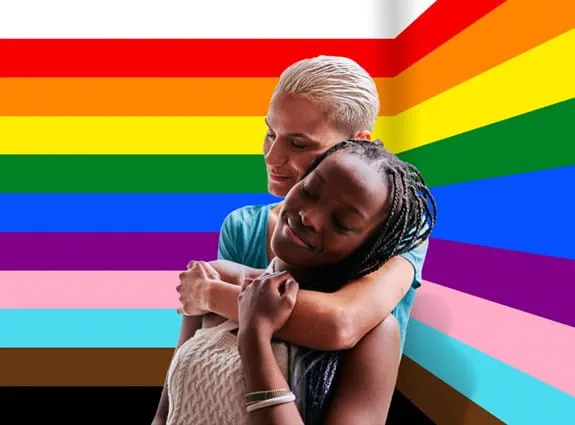 Two people in front of coloured strips of pride flag