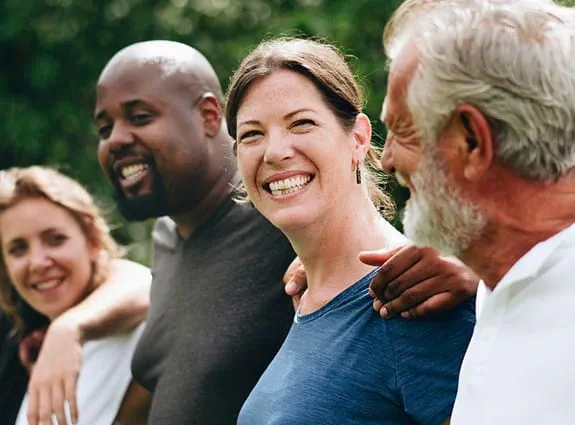 A group of people lined up together with arms around shoulders, smiling