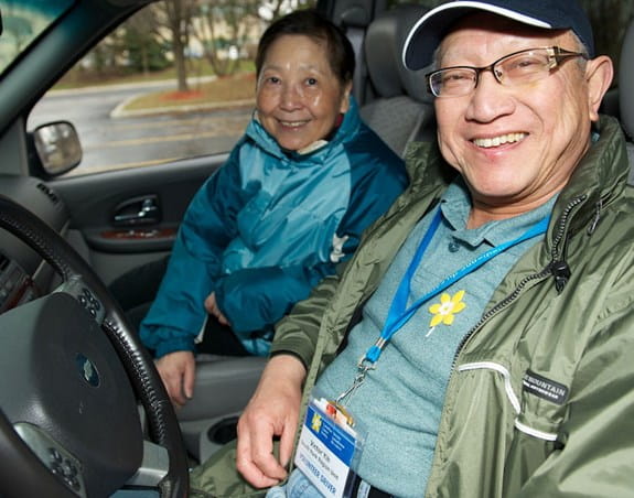An older smiling couple sitting in a car.  