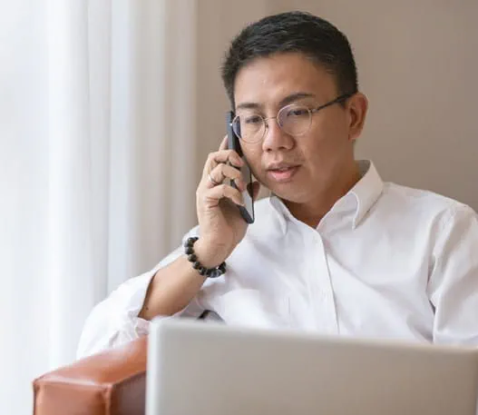 A man talks on his cell phone near his laptop