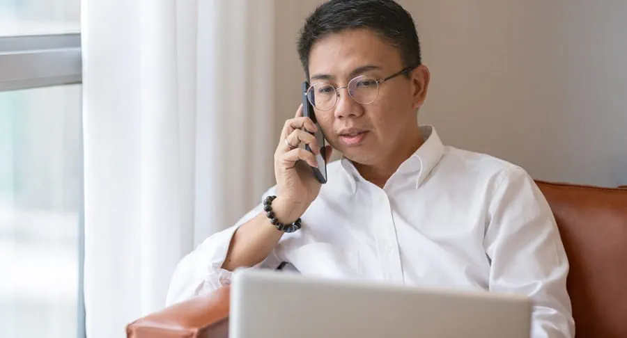 A man talks on his cell phone near his laptop