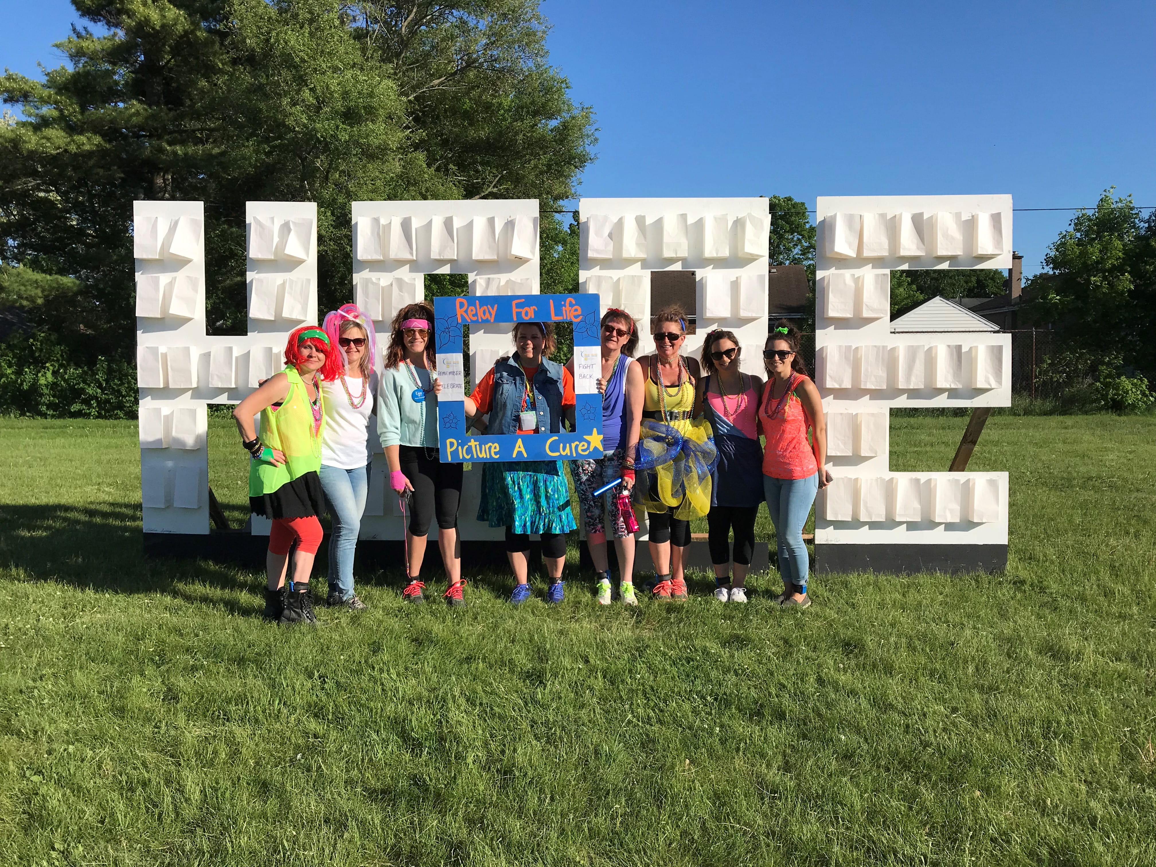 Dianne in a group standing in front of a sign that says “HOPE” at Relay For Life in 2018 