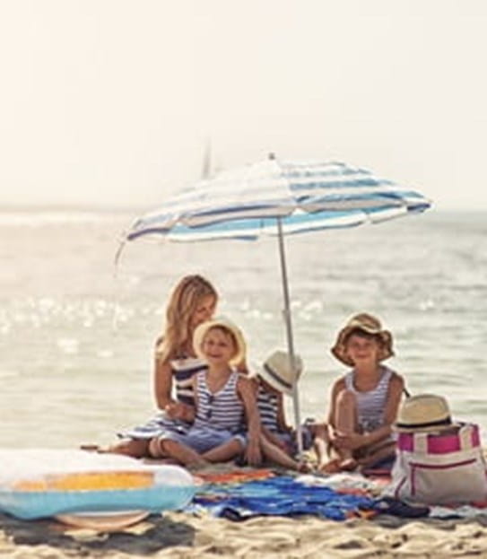 Family sitting on a beach under a sun umbrella 