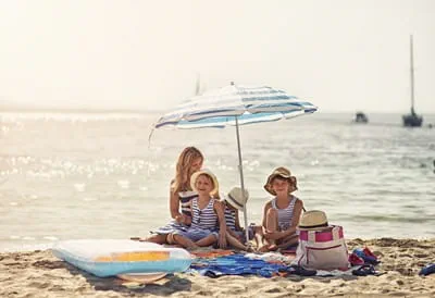 Family sitting on a beach under a sun umbrella 