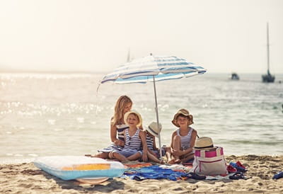 Une famille assise sur la plage, sous un parasol