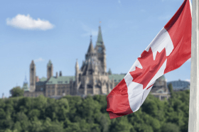 Canadian flag flying with Parliament Hill in the background