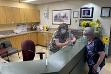 A lodge employee is wearing a facial mask and standing behind plexiglass.