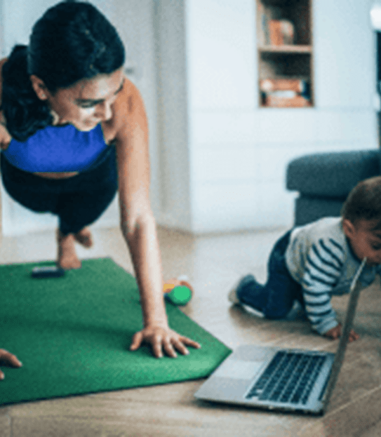 A mom exercises while her child plays on the floor next to her.