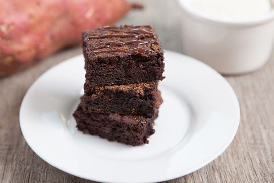 A close up of three chocolate sweet potato bars stacked on a plate