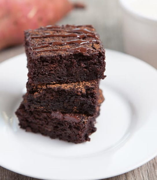 A close up of three chocolate sweet potato bars stacked on a plate