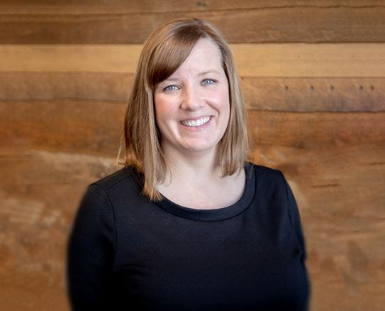 elly Masotti, Vice President of Advocacy at CCS smiling in front of a wood wall.