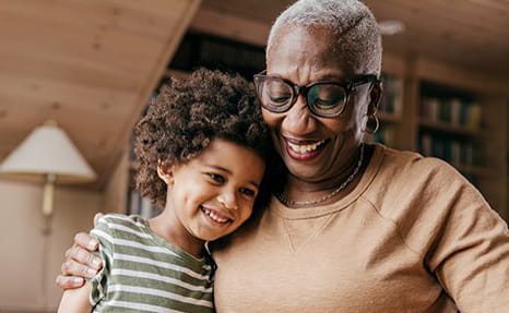 A grandmother tenderly embraces her grandson. 