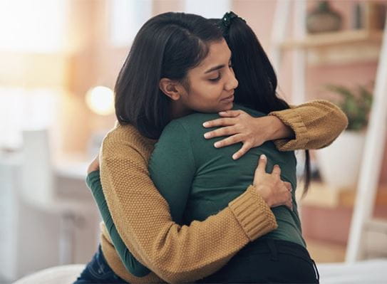 Two women embrace each other in a hug