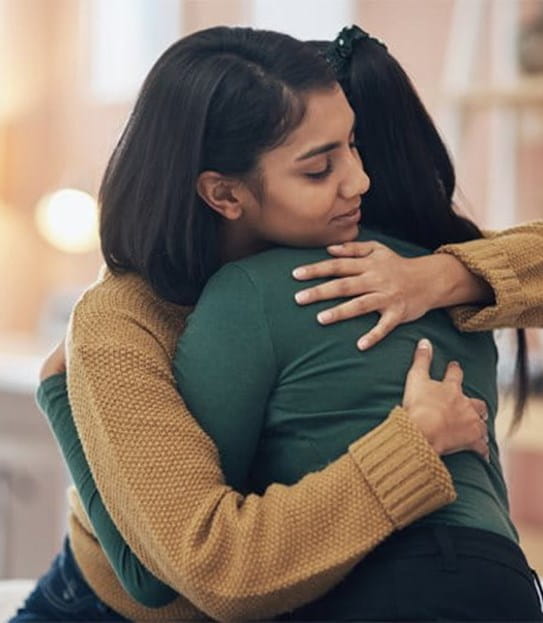 Two women embrace each other in a hug
