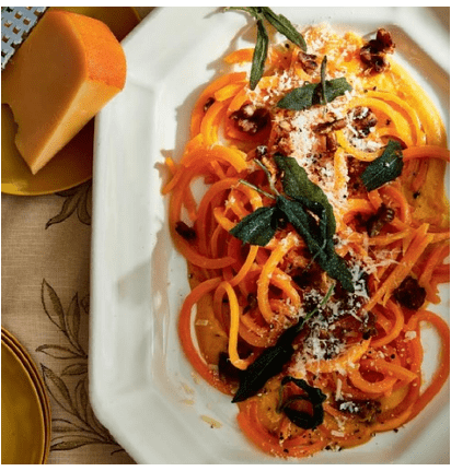 A plate of butternut squash topped with fried sage anda grated gouda cheese.