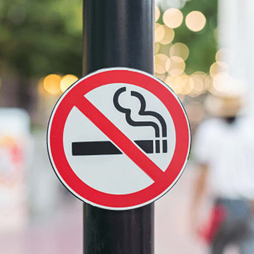 A no smoking sign on a pole with a blurry background