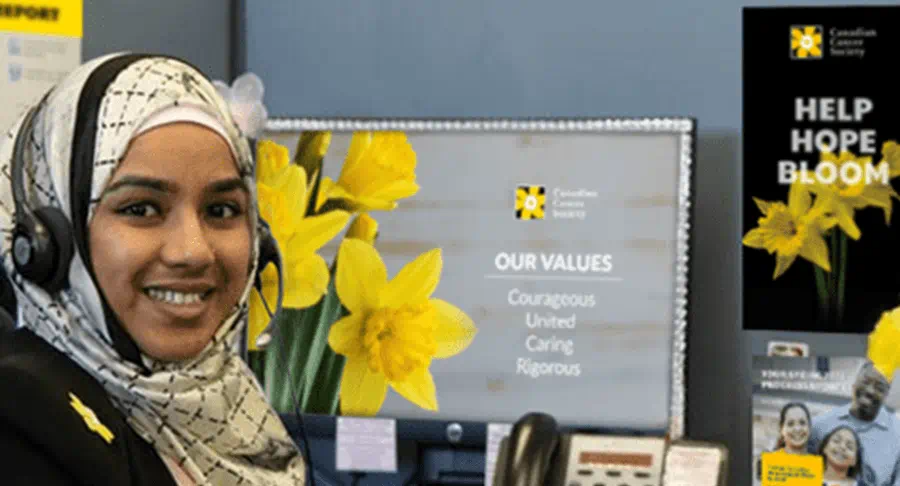 A woman wearing a headset smiles while sitting at her desk in a call centre