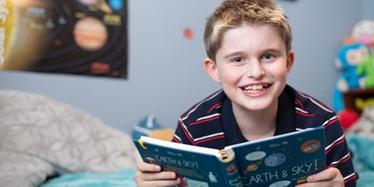 Harland, childhood cancer survivor reading a book.