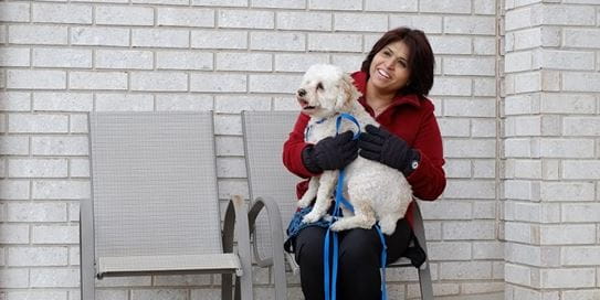 Sharon Sandhawalia holding a dog and smiling