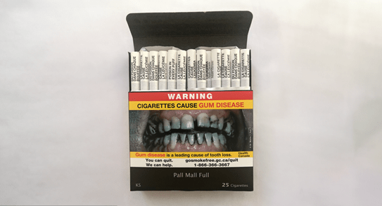 An open pack of cigarettes, with a warning label on the front and warning labels on each individual cigarette.
