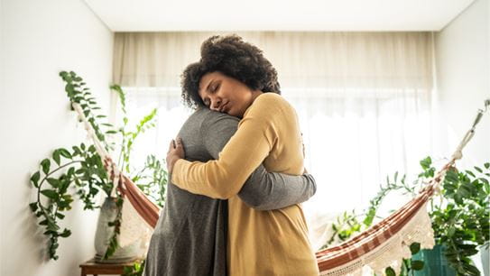 Deux personnes s'embrassant dans une pièce lumineuse décorée de plantes