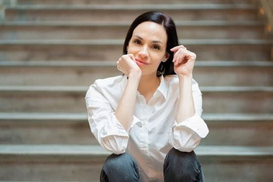 Vanessa, assise sur les marches d’un escalier, les bras posés sur les genoux