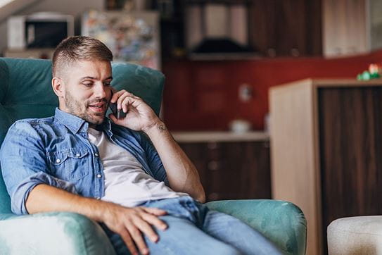 A person on the phone sits in an armchair