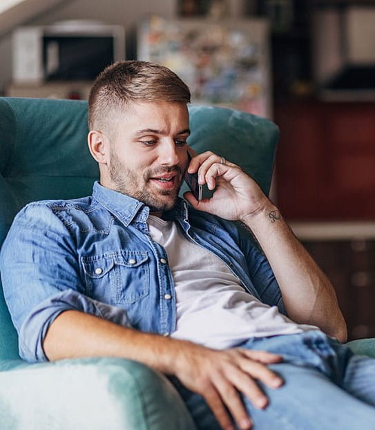 A person on the phone sits in an armchair