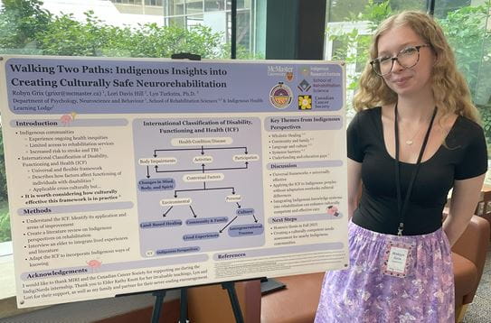 Robyn stands next to an easel displaying her research poster.