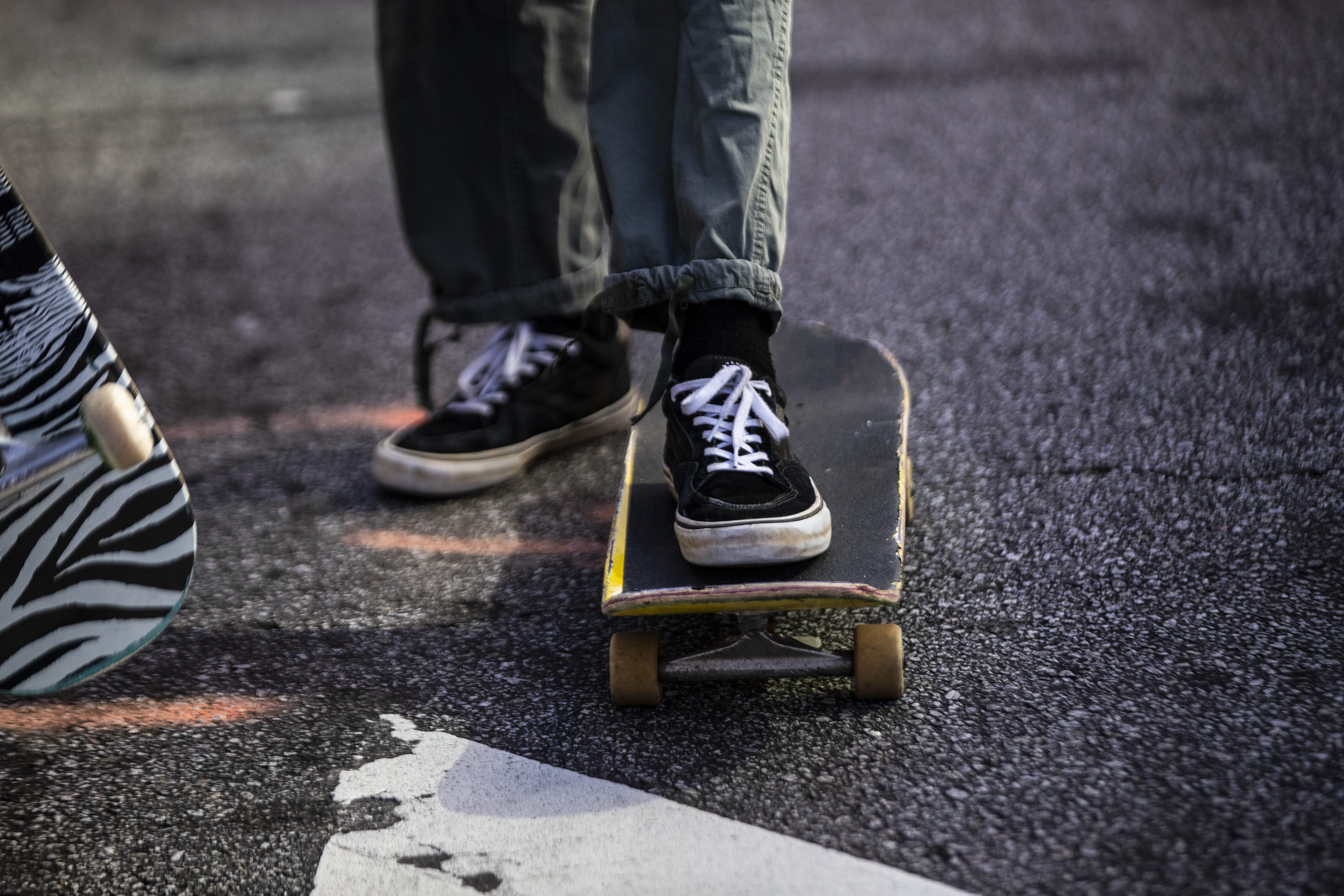 Une personne se tient debout, un pied sur une planche à roulettes et l’autre sur l’asphalte.