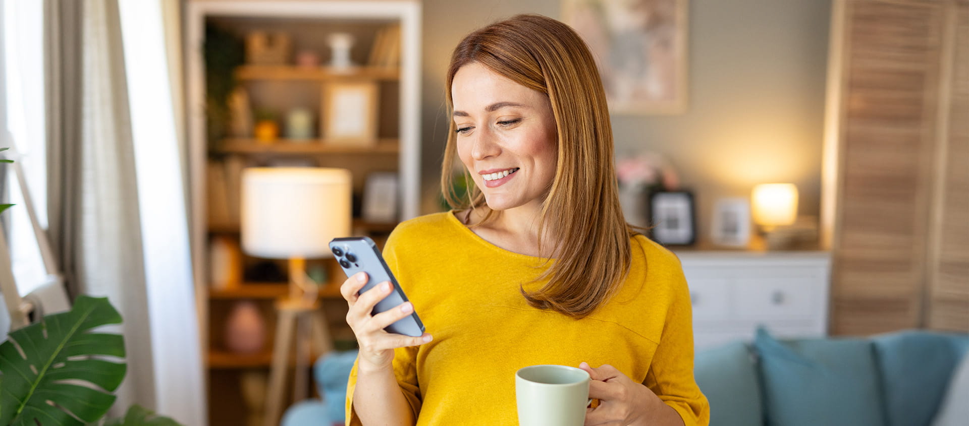 A person in their home looks at their phone and smiles.
