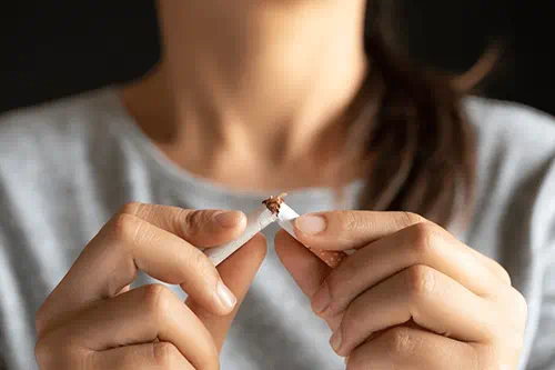 A photo of a woman holding a cigarette broken in half