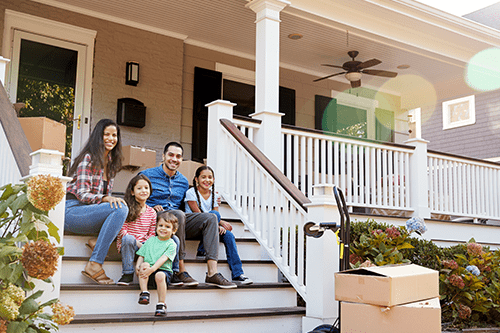 A family of five sitting on the front steps of their home