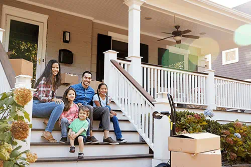 Les membres d’une famille sont assis à l’extérieur, dans l’escalier menant à leur maison.