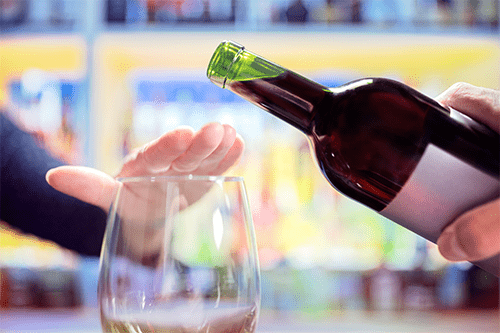 Une personne recouvre de la main le dessus d’une coupe vide pour empêcher qu’on y verse du vin.