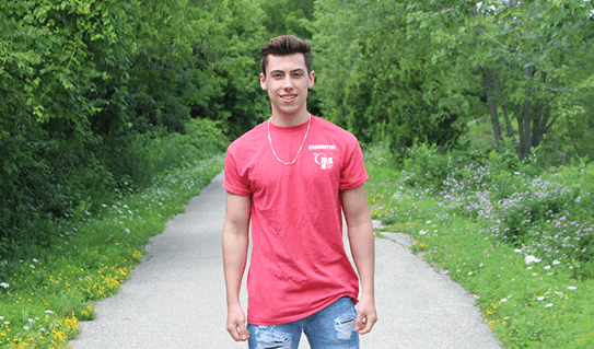 Jacob smiling and wearing a CCS volunteer shirt