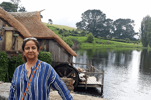 Anjum standing infront of a house by a lake