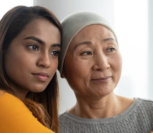 A cancer patient being hugged by their caregiver