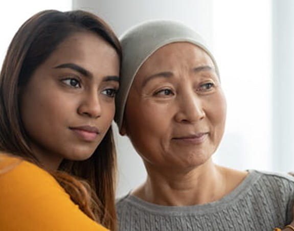 A cancer patient being hugged by their caregiver