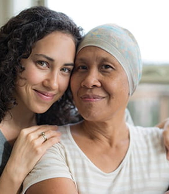 A daughter sitting behind her mother with her hands on her shoulder