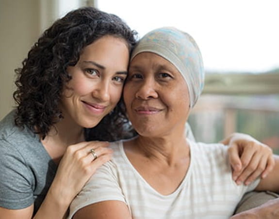 A daughter sitting behind her mother with her hands on her shoulder