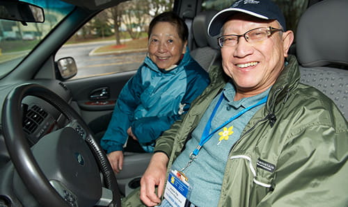 A volunteer and a cancer patient smiling in a car