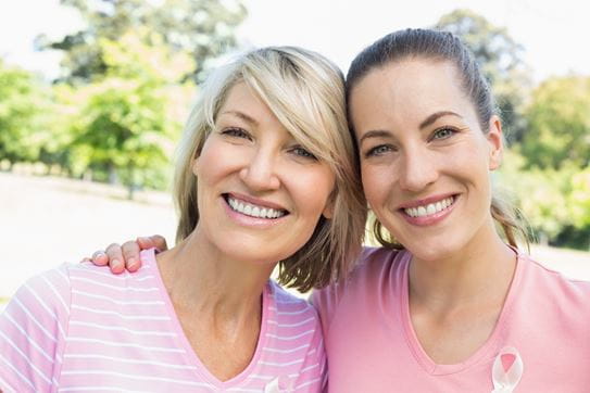 Deux femmes portant des chandails roses en train de sourire