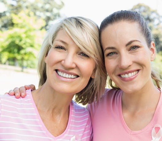 Two smiling women wearing pink shirts