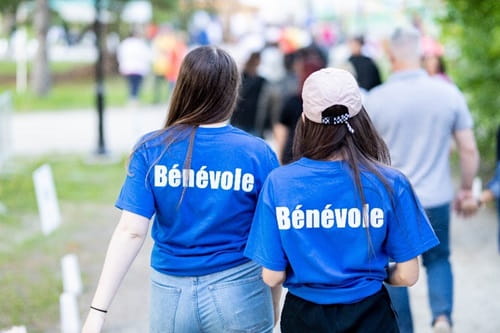Deux jeunes femmes portent des chandails affichant le mot Bénévole à l’arrière