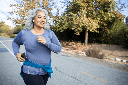 An older woman jogging down the road