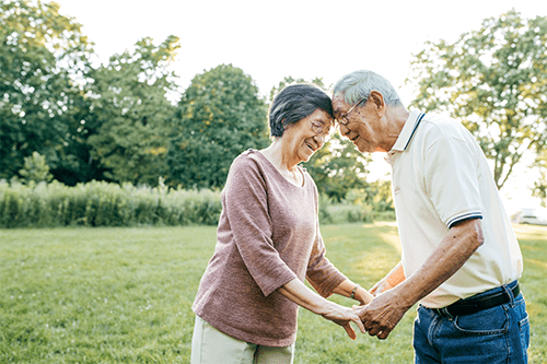An older couple facing each other and holding hands