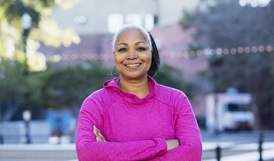 A woman wearing a pink long-sleeve shirt smiling at the camera 